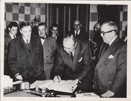 Paul Sauvé signe un livre sous le regard attentif de Maurice Duplessis et d'autres hommes.